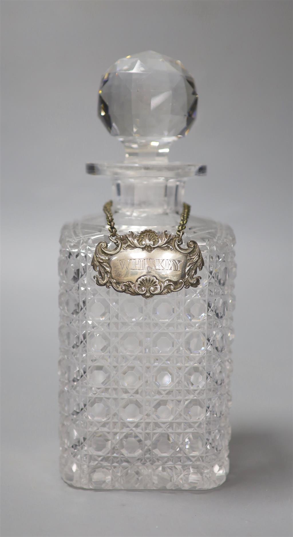 A George IV silver Whiskey label by John Riley 1824 and a cut glass decanter, height 24cm